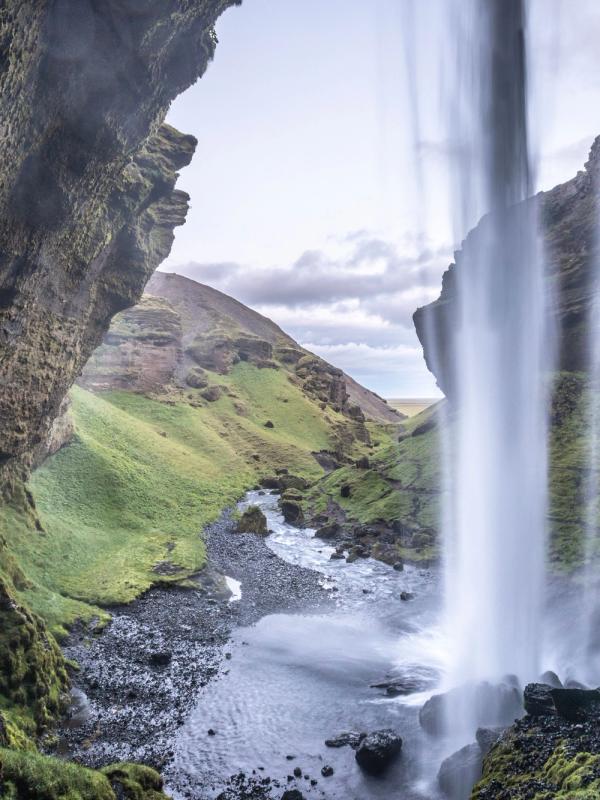 Cascada Kvernufoss vista desde atrás en un día soleado