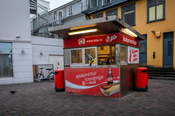 a hot dog stand with a coca cola advertisement on the side of it
