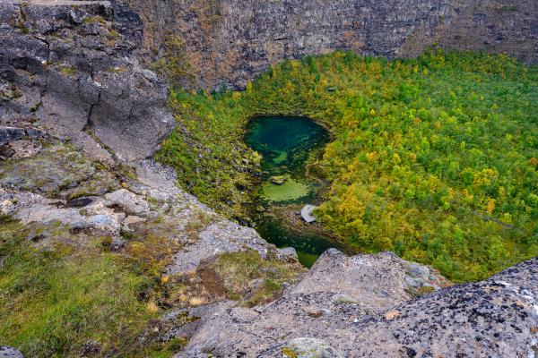 Pond in the middle of a green forest surrounded by cliffs