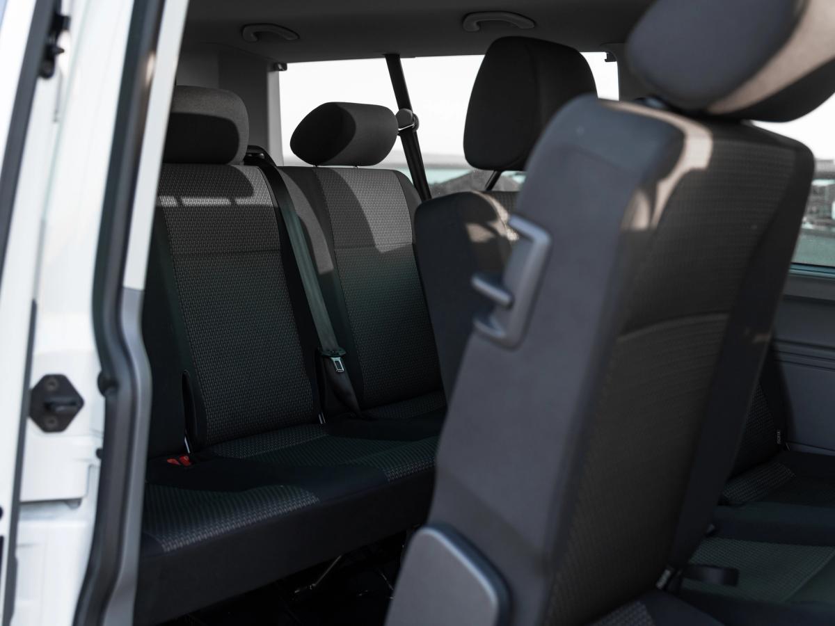 Rücksitze des Volkswagen Caravelle Rücksitzbank und umklappbare mittlere Sitzreihe eines Volkswagen Caravelle, durch die offene Tür gesehen