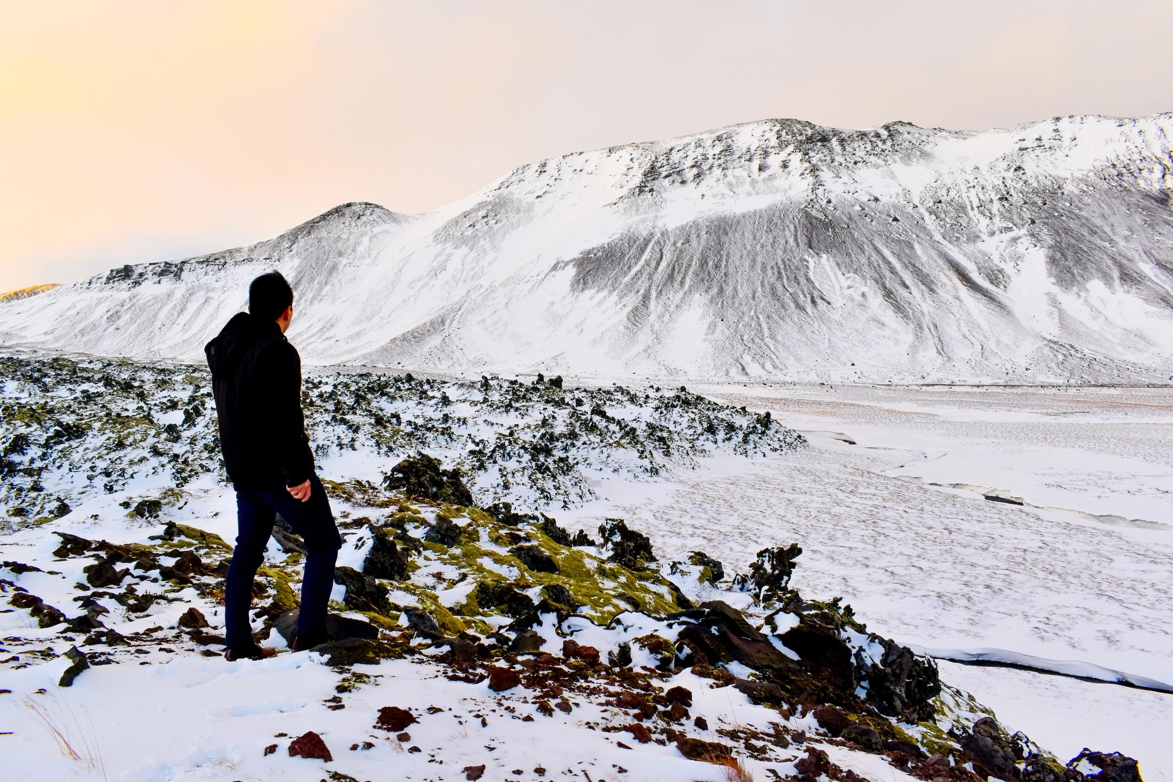 a man is standing on top of a snow covered mountain .
