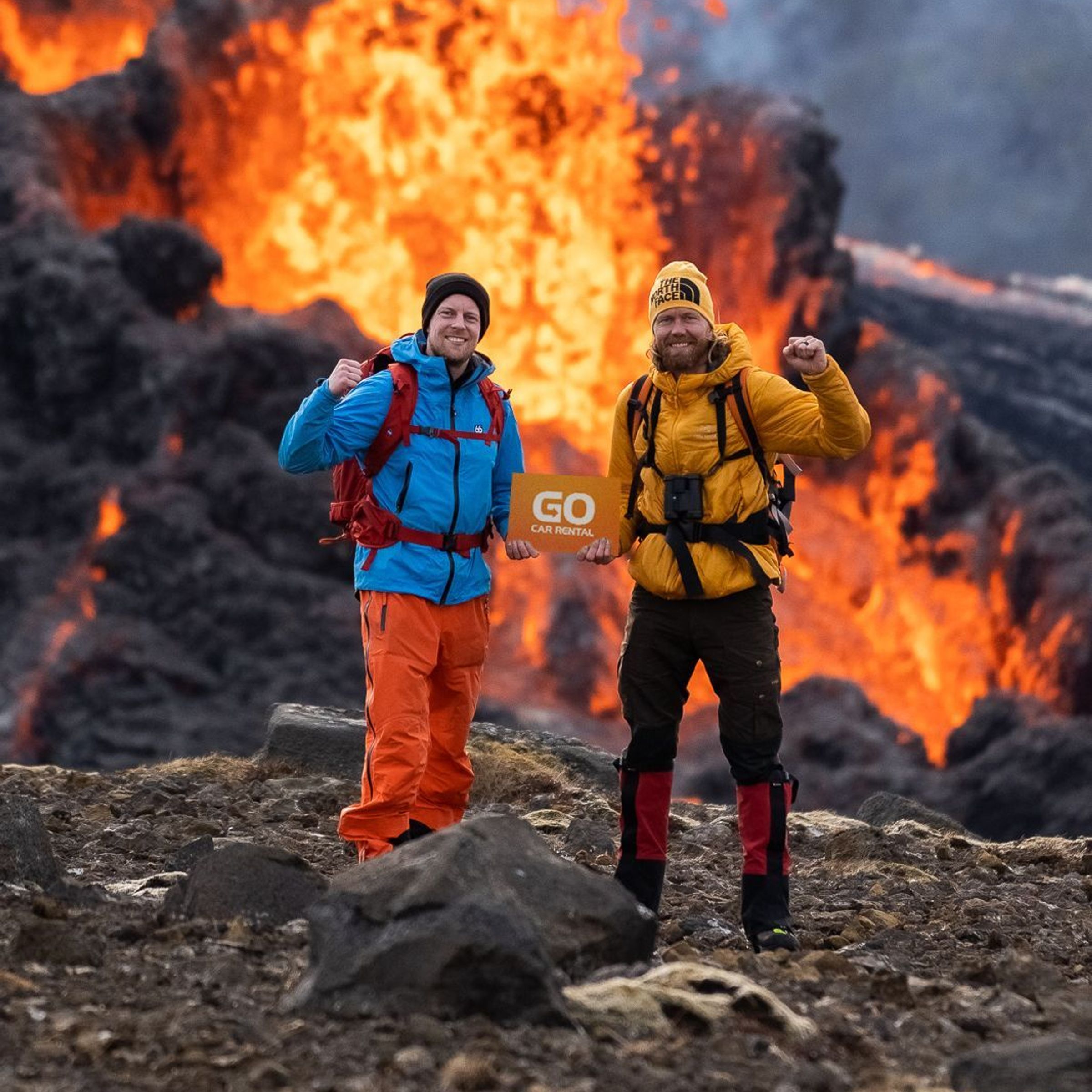 two men standing in front of a volcano with a sign that says go