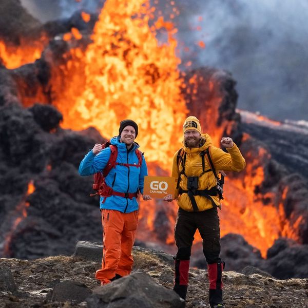 two men standing in front of a volcano with a sign that says go