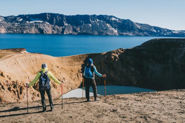 two people are hiking in the mountains near a crater lake, Askja