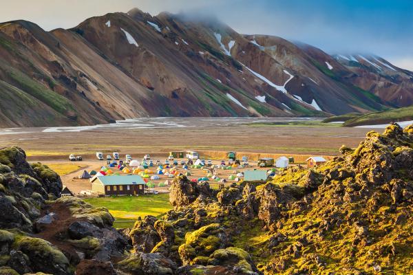 a group of tents are sitting in a field with mountains in the background, Landmannalaugar