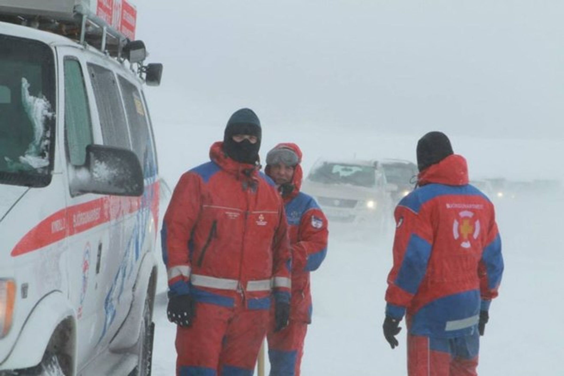 a group of people are standing in front of a van in the snow .