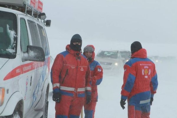 a group of people are standing in front of a van in the snow .