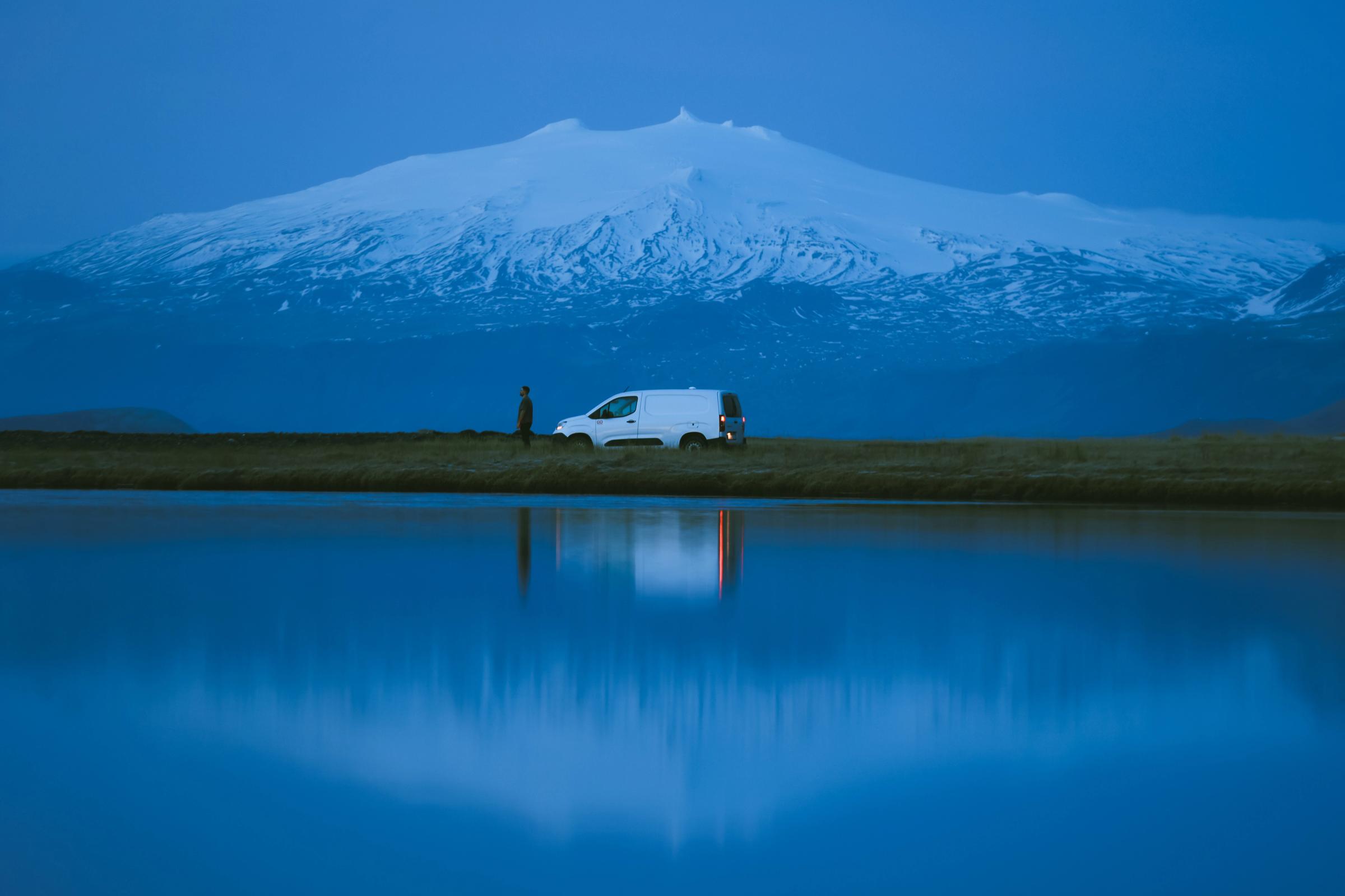 Ein kompakter Campervan für 2 Personen am Wasser, in dem sich ein großer Berg spiegelt, Campervan-Vermietung Island