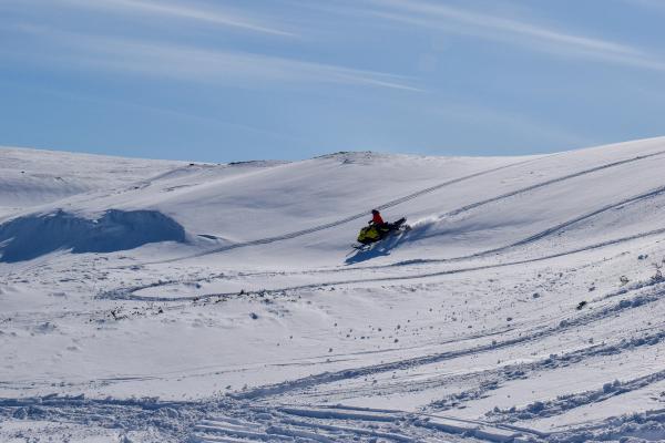 a person is riding a snowmobile down a snow covered hill in iceland.