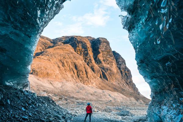Person standing by the entrance of an ice cave