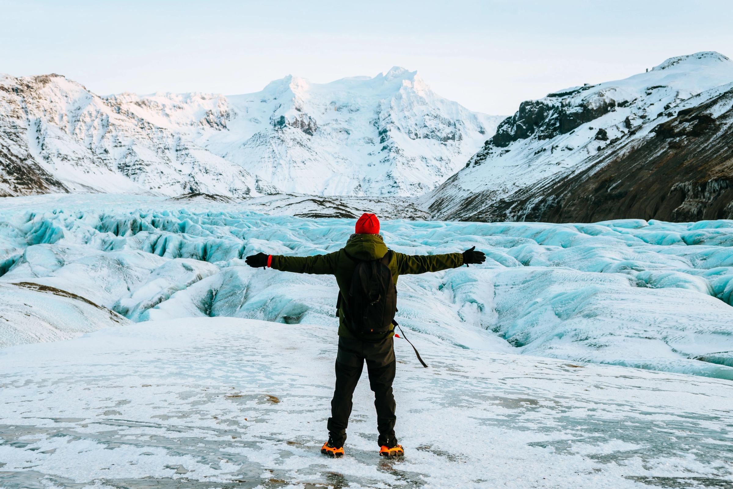 Man on top of a glacier stretching his arms