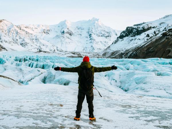 Man on top of a glacier stretching his arms