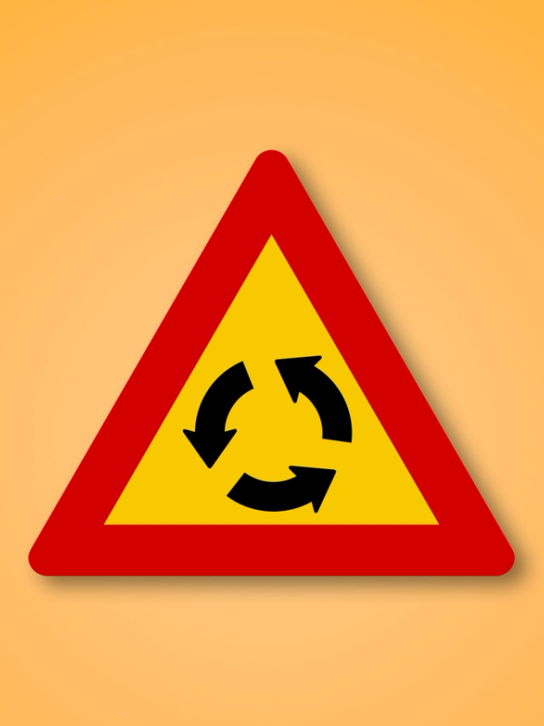 Red and yellow triangle road sign with an Roundabout in the middle. This road sign means Roundabout ahead