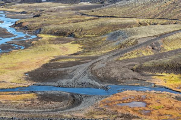 an aerial view of a river running through a lush green valley in iceland.