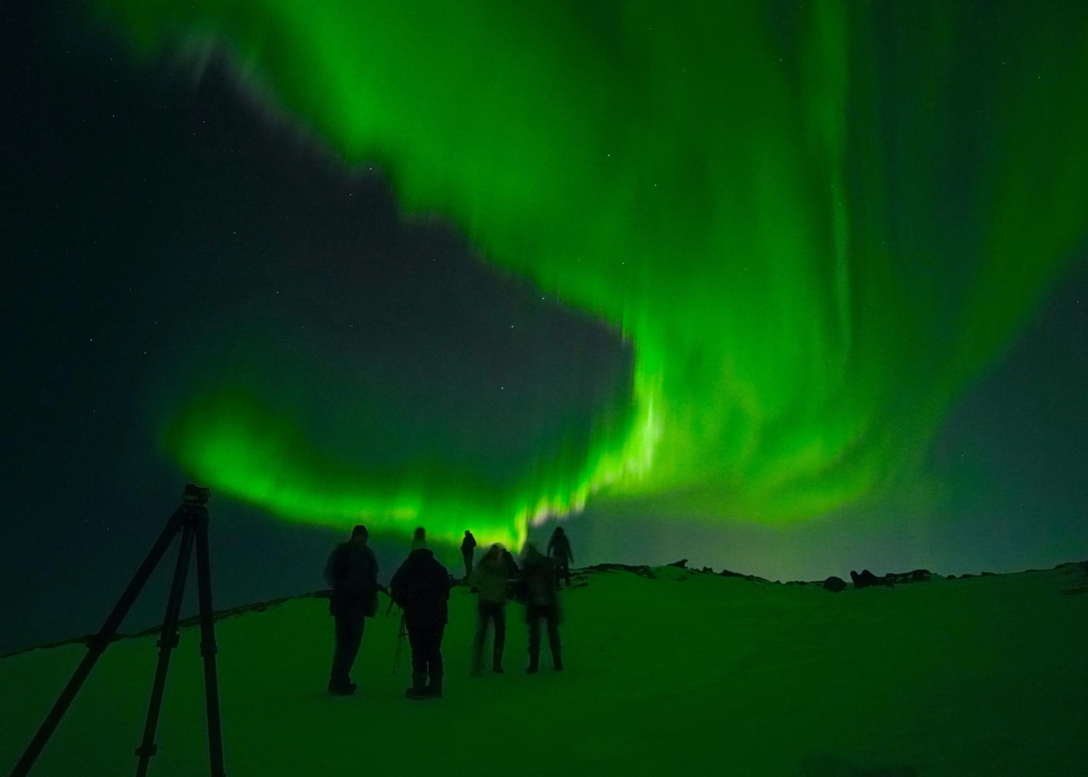 Grupo de personas bajo la aurora boreal en Islandia