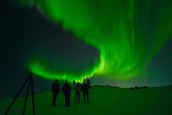 Grupo de personas bajo la aurora boreal en Islandia