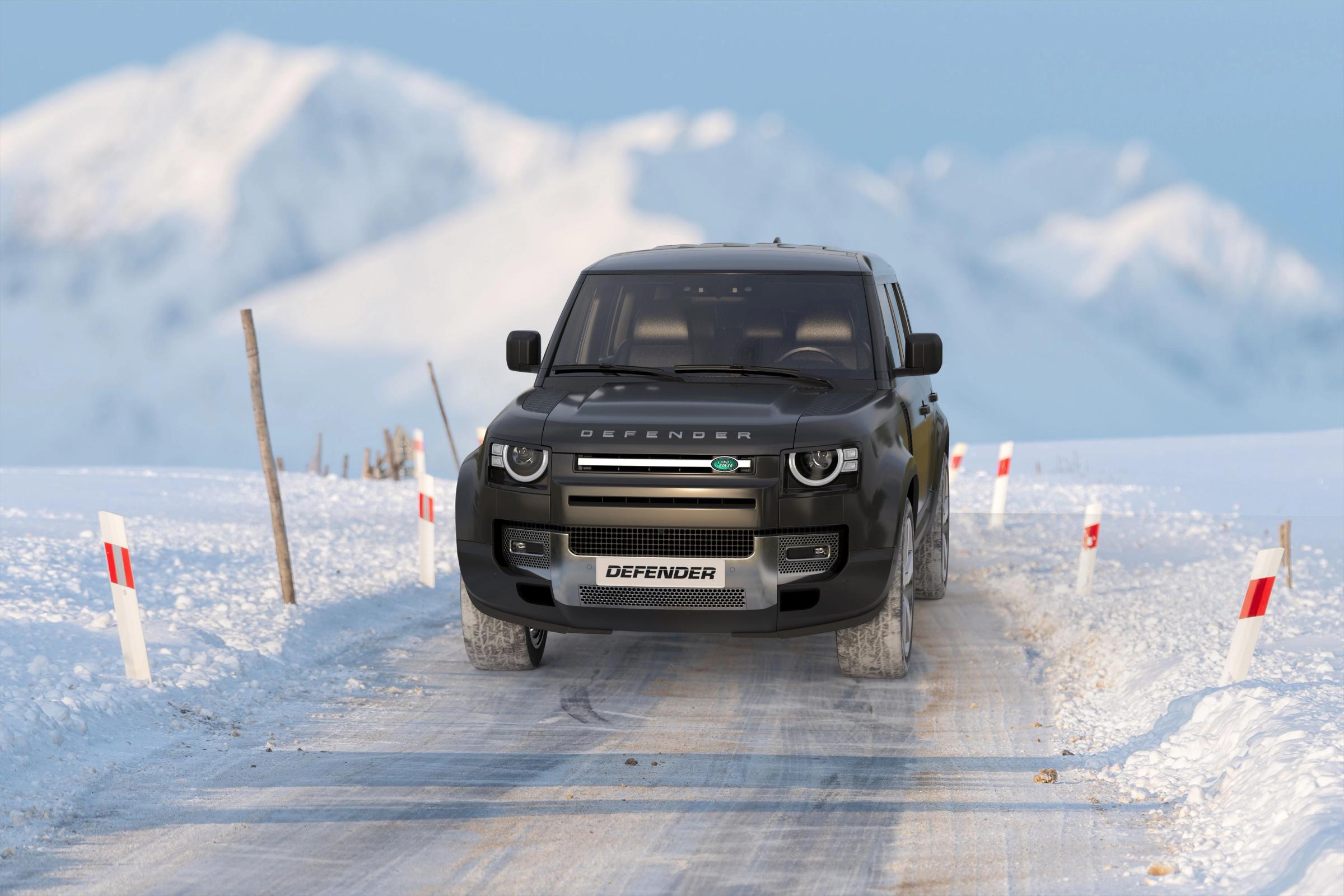 Dark Land Rover Defender SUV driving on a snowy mountain road.