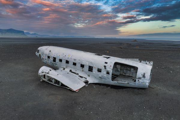 a wrecked airplane is laying in the middle of a desert in sΓ³lheimasandur in iceland.