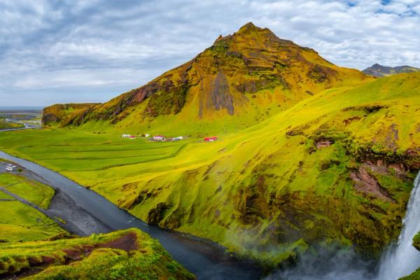 a waterfall in the middle of a lush green valley with a mountain in the background .