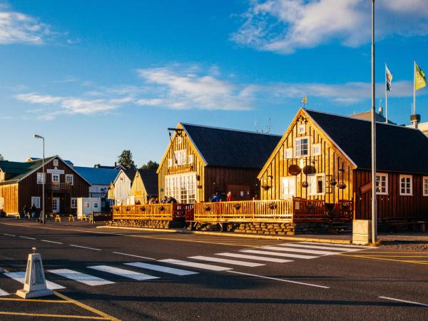 une rangée de maisons en bois côte à côte au bord d'une route, Husavik