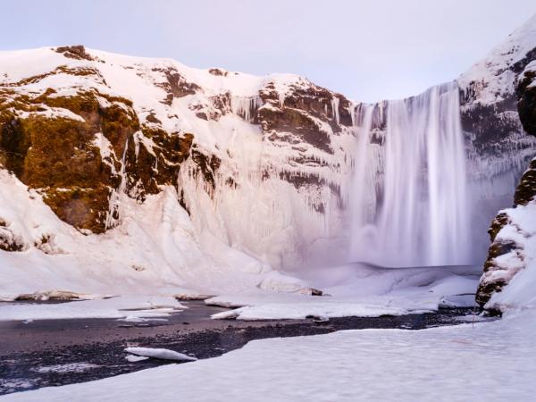a waterfall during winter with surroundings covered by snow