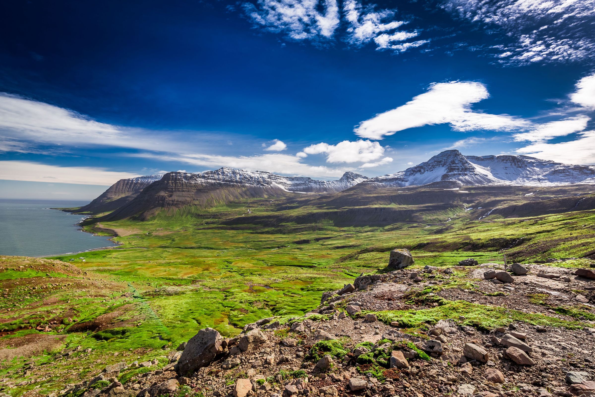un paisaje co grandes montañas rocosas con el mar a la izquierda