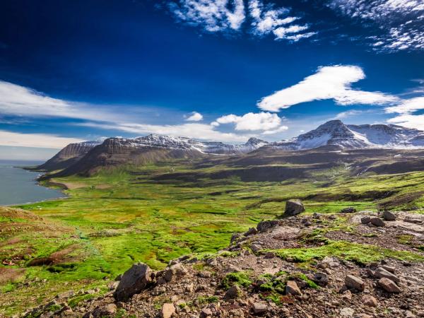 a view of a valley with mountains in the background and a body of water in the foreground .