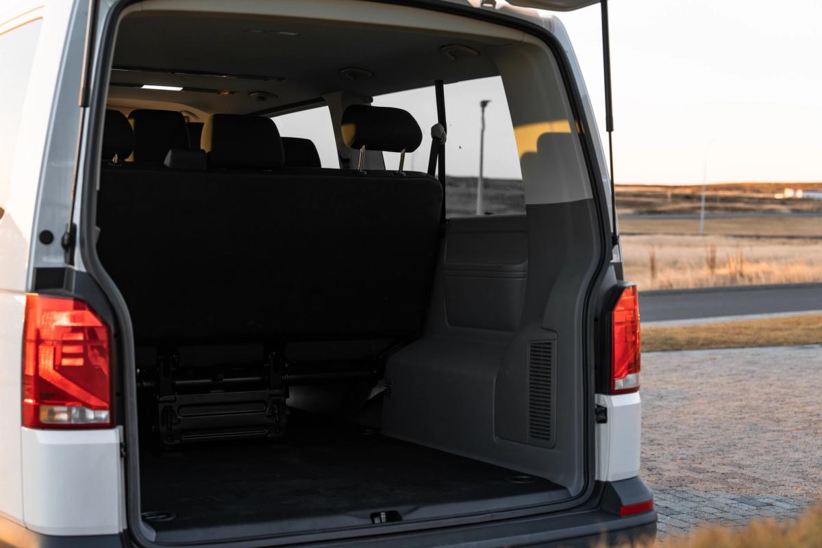 Volkswagen Caravelle mit geöffneten Hecktüren und Blick auf den Gepäckraum mit umgeklapptem Sitz hinter den Rückleuchten
