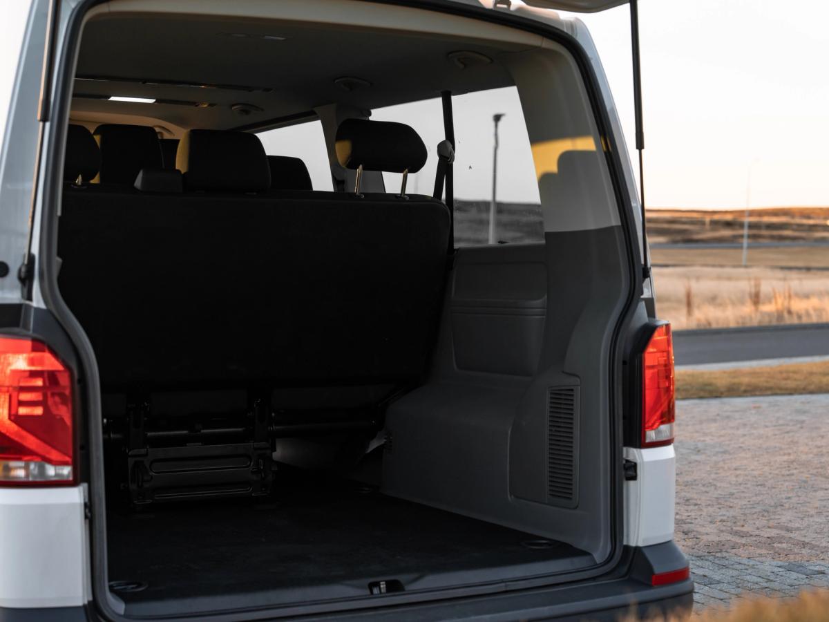 Hinterer Laderaum des Volkswagen Caravelle Volkswagen Caravelle mit geöffneten Hecktüren und Blick auf den Gepäckraum mit umgeklapptem Sitz hinter den Rückleuchten