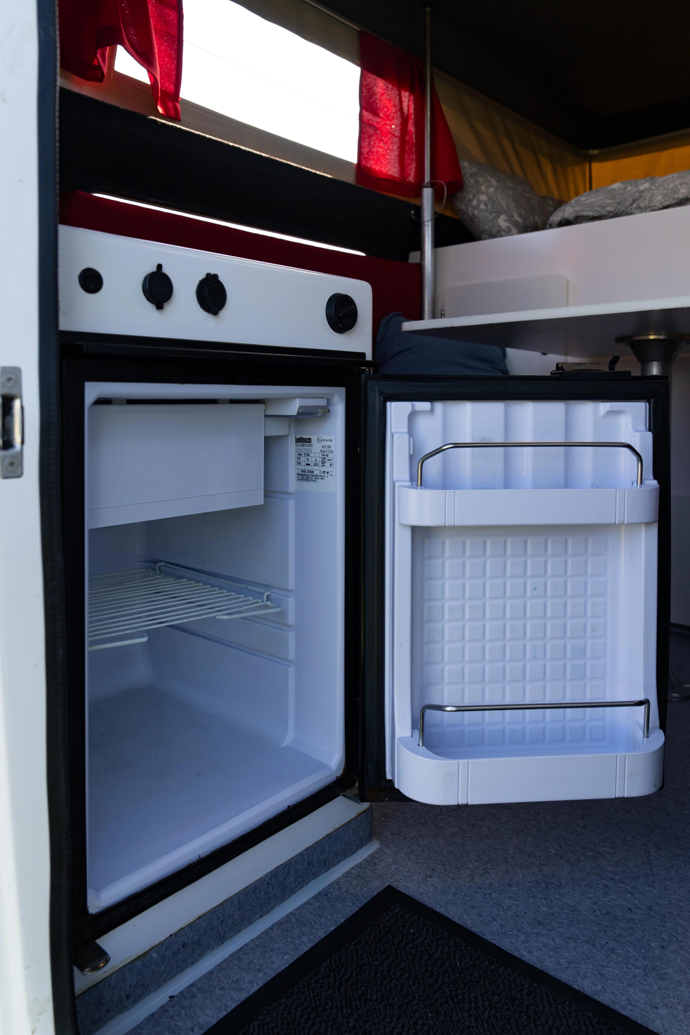 Fridge Door Open Open fridge with top compartment, wire shelf and door racks below the stove controls