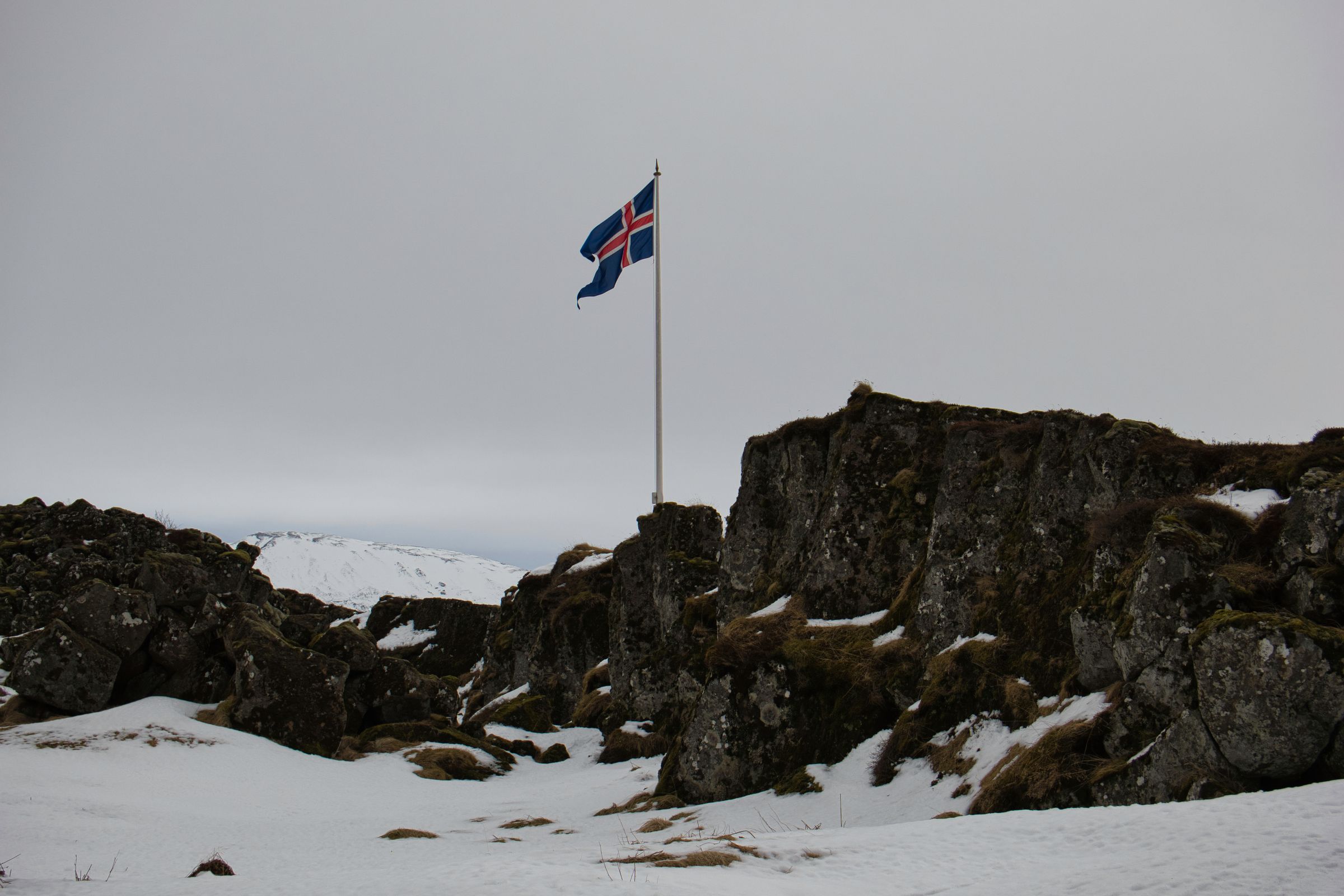 a flag is flying in the wind on top of a snow covered hill .