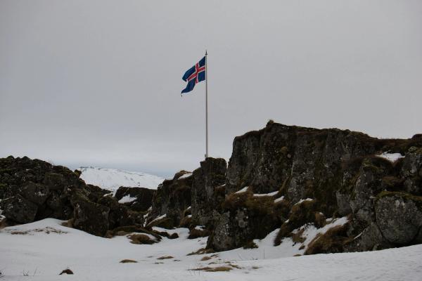 a flag is flying in the wind on top of a snow covered hill .