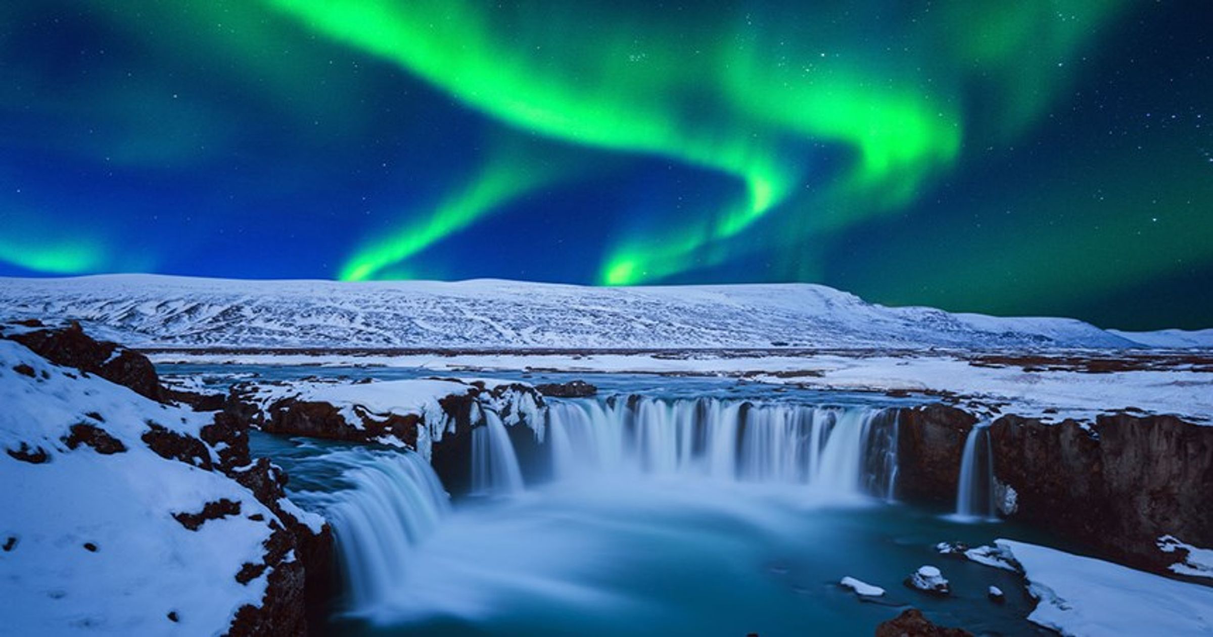 Goðafoss completamente nevada bajo la aurora boreal