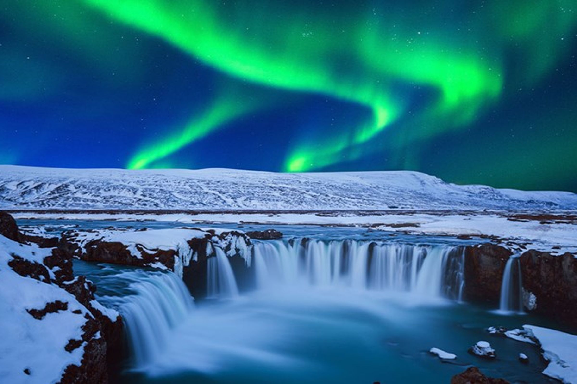 Goðafoss completamente nevada bajo la aurora boreal
