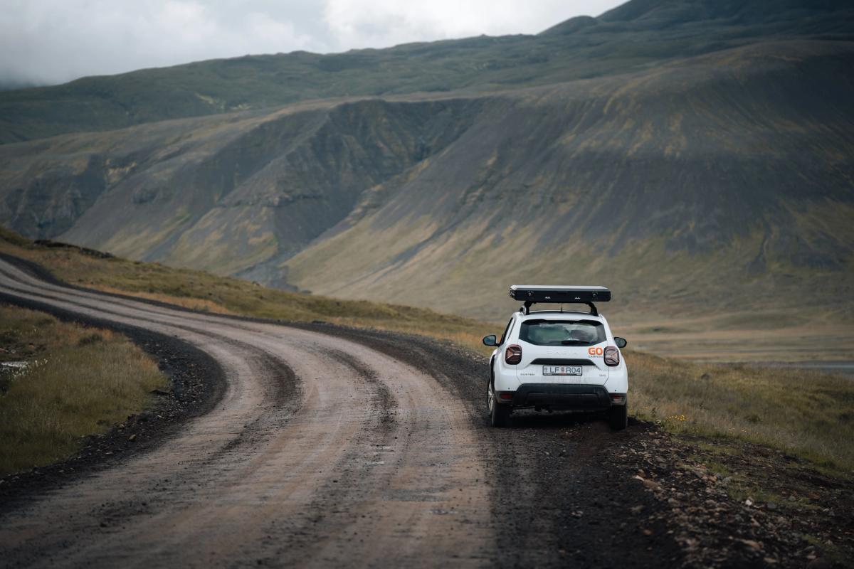an aerial view of a white van driving down a dirt road in the desert .