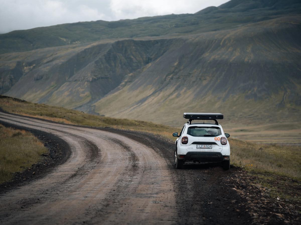 an aerial view of a white van driving down a dirt road in the desert .