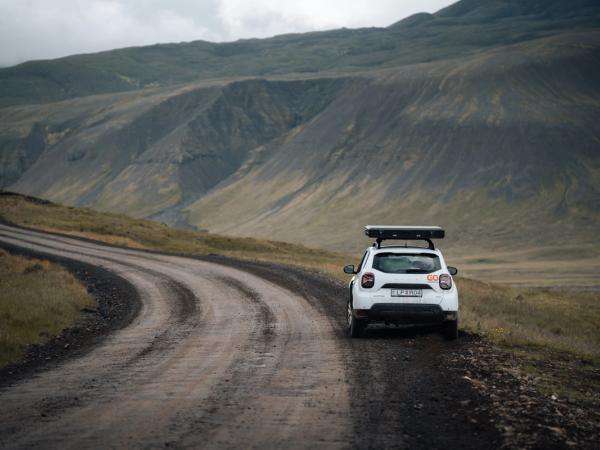Coche blanco parado en el lado derecho de una carretera de tierra