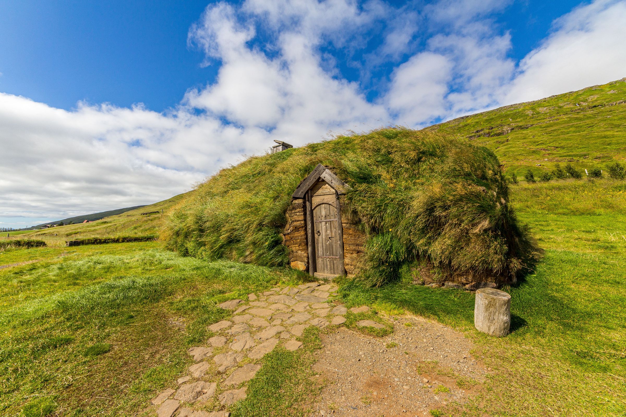 a small wooden house is sitting on top of a grass covered hill .