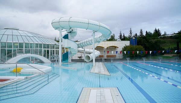 there is a water slide in the middle of a swimming pool .