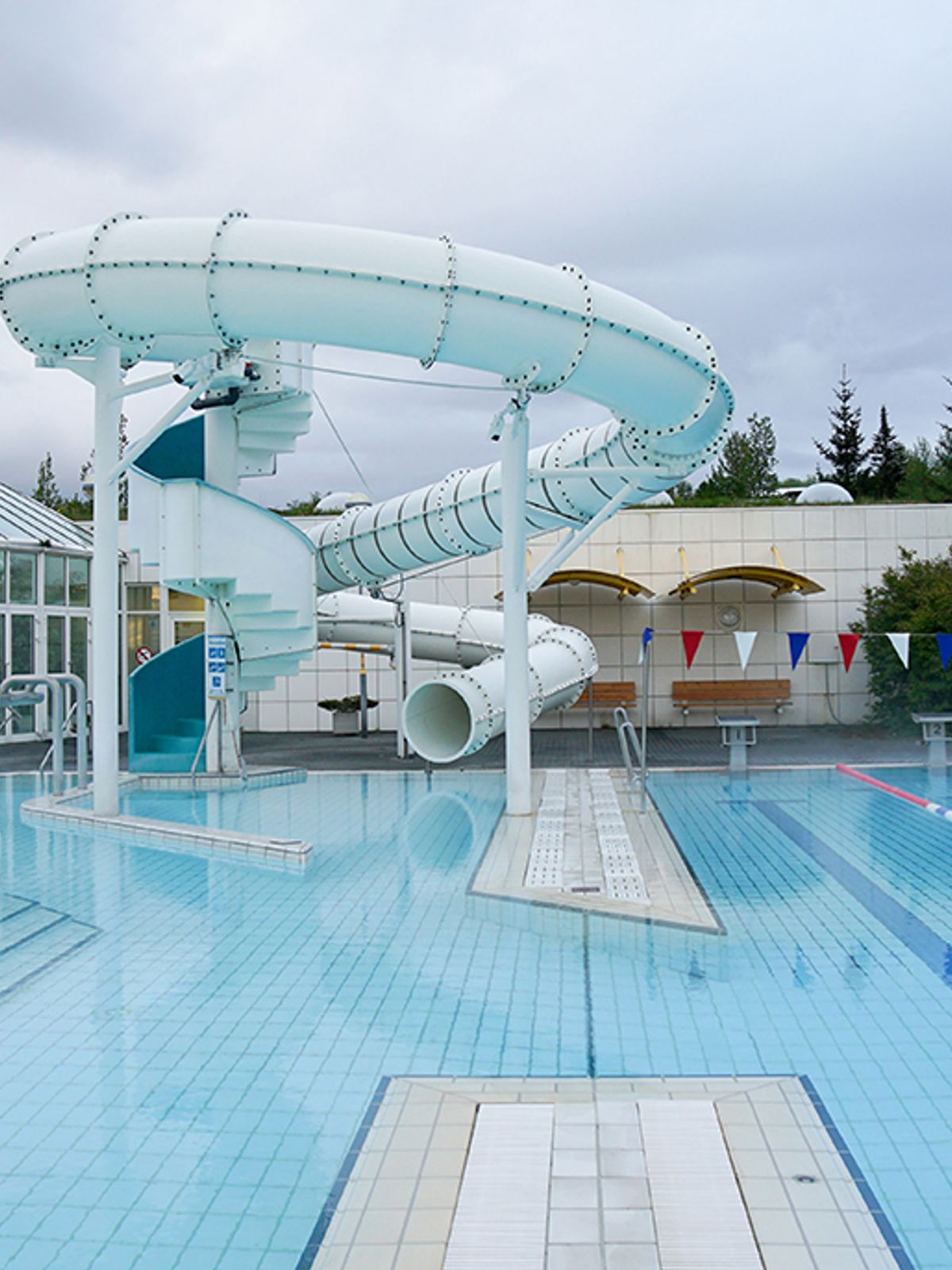 there is a water slide in the middle of a swimming pool .