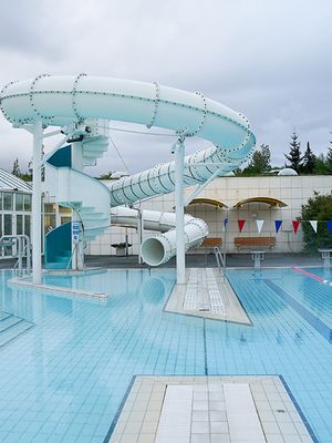 there is a water slide in the middle of a swimming pool .