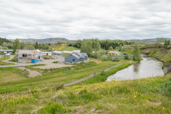 un pequeño pueblo con un río que lo atraviesa y casas al fondo.