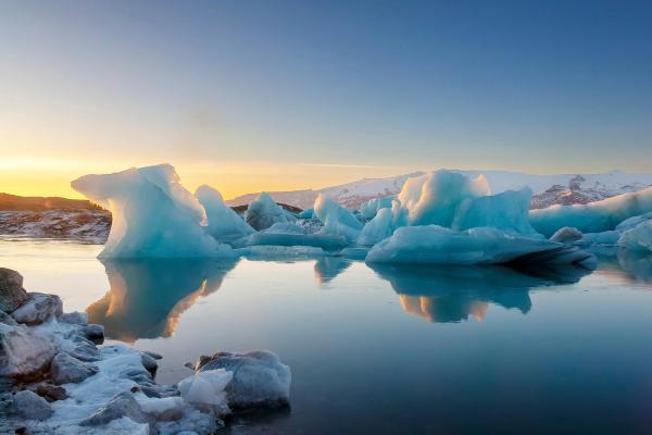 icebergs are floating in a lake at sunset .