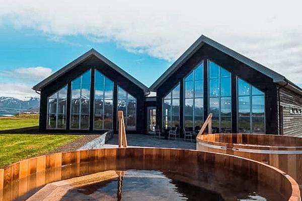 a wooden hot tub is sitting in front of a house with a lot of windows, Beer Spa in Iceland