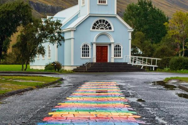 un camino de ladrillos de colores de arcoíris conduce a una iglesia
