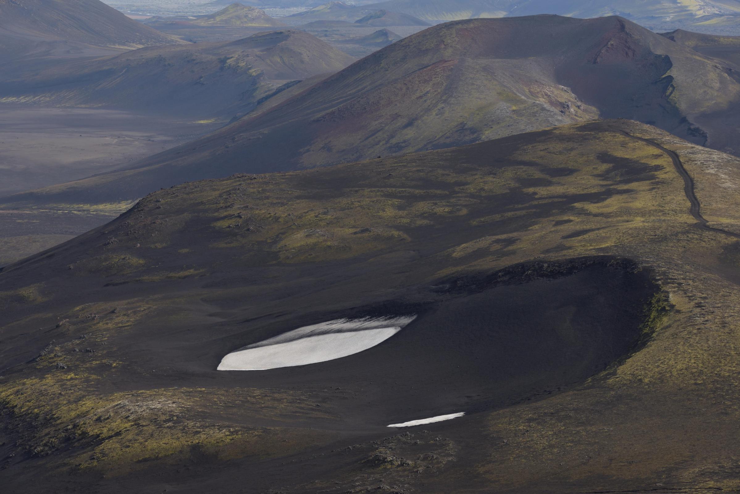 an aerial view of a small lake in the middle of a mountain .