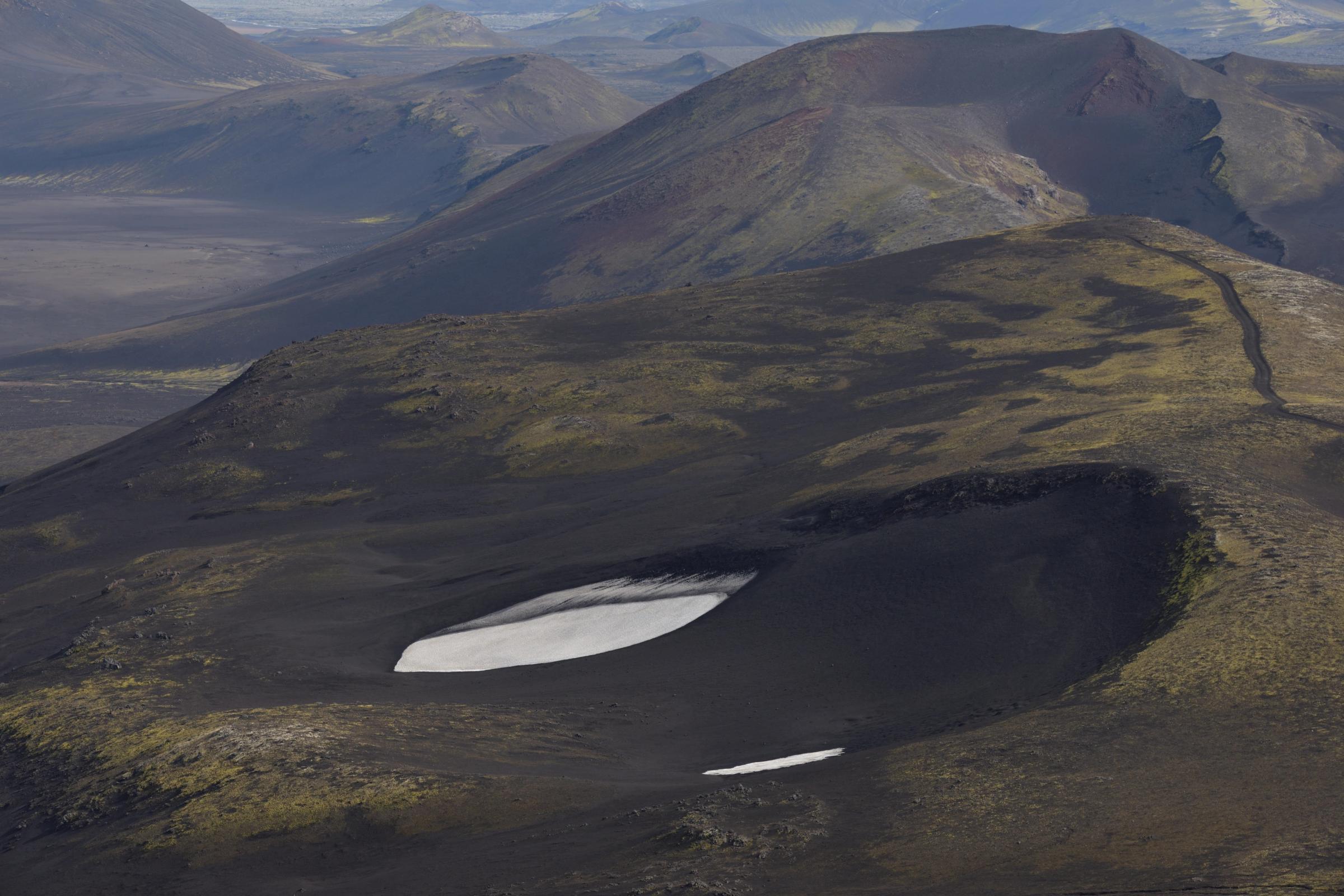 an aerial view of a small lake in the middle of a mountain .