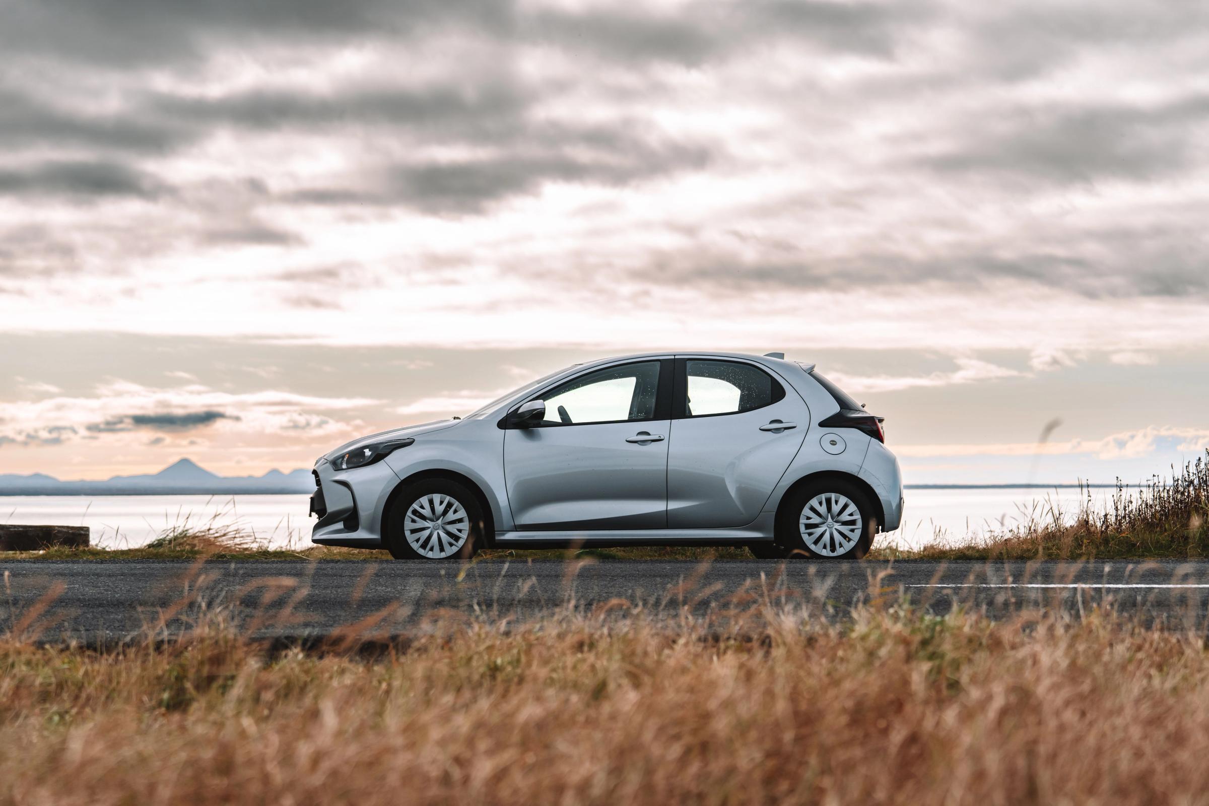 Toyota Yaris compact car side view parked on a coastal road with open water