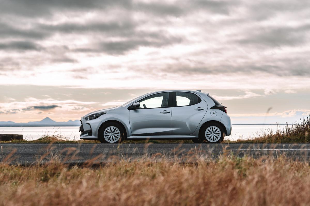 Toyota Yaris compact car side view parked on a coastal road with open water