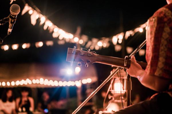 a man is playing an acoustic guitar on a stage at night .